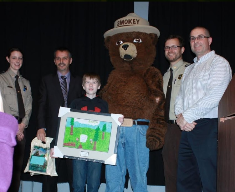 MHA Derrick Bragg and staff from the Forest Service Branch of Government present Braeden Mouland and Principal Jerry Jenkins with their prizes (Photo credit: Natasha Mouland)